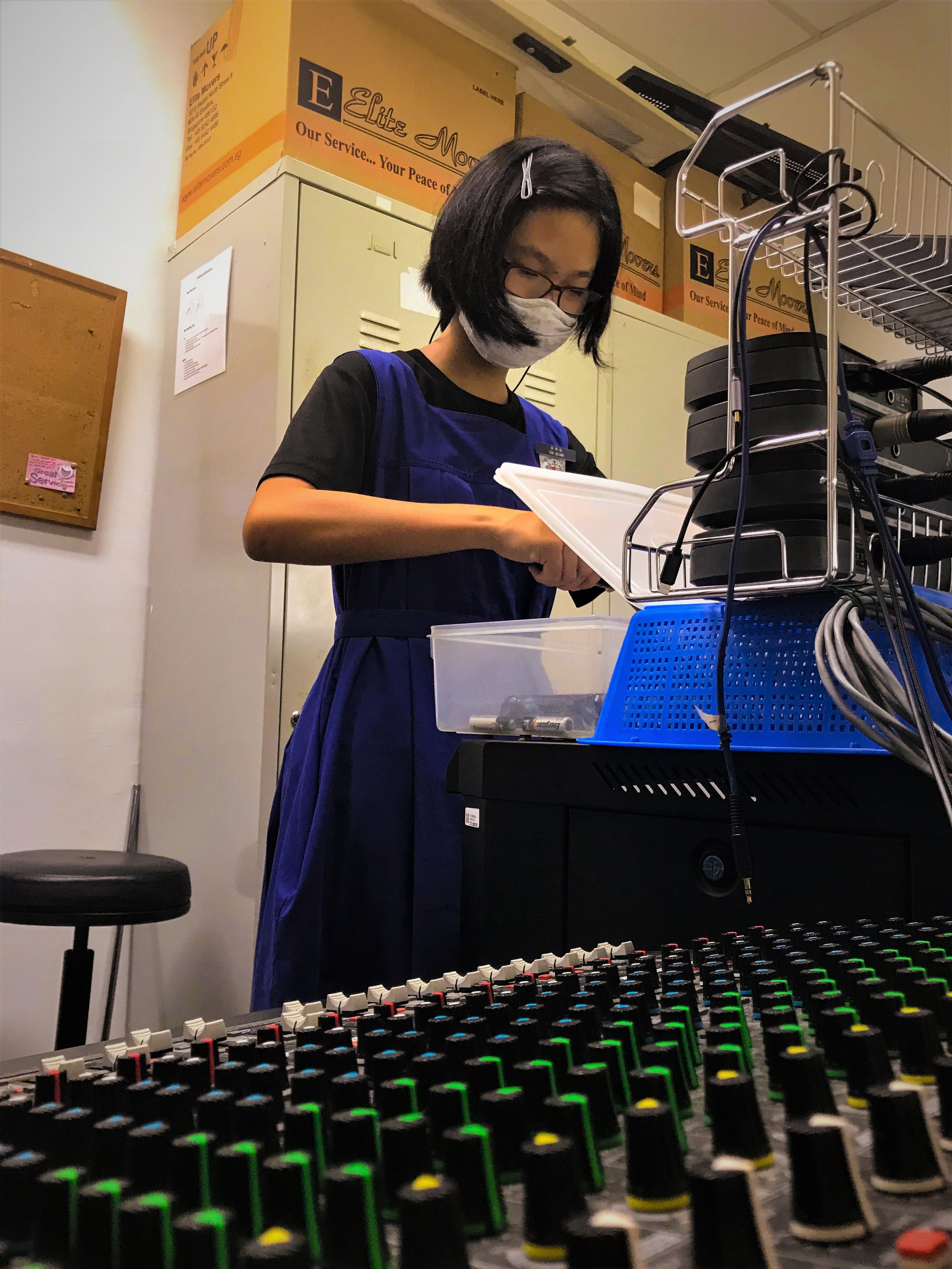 Student on PA duty checking equipment near sound mixing console.